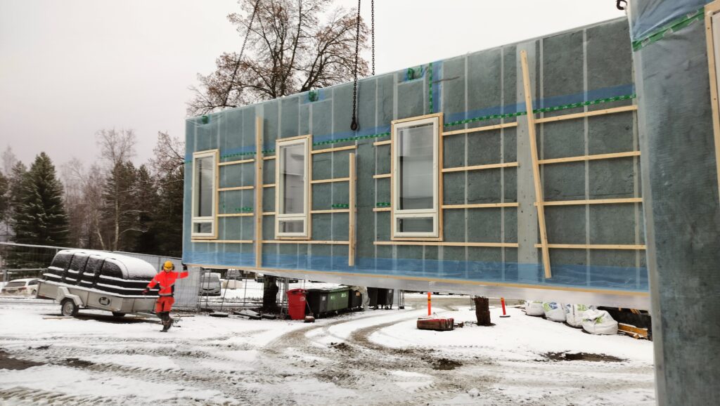 Seinäelementtiä lasketaan työmaalla maahan nosturin avustuksella.